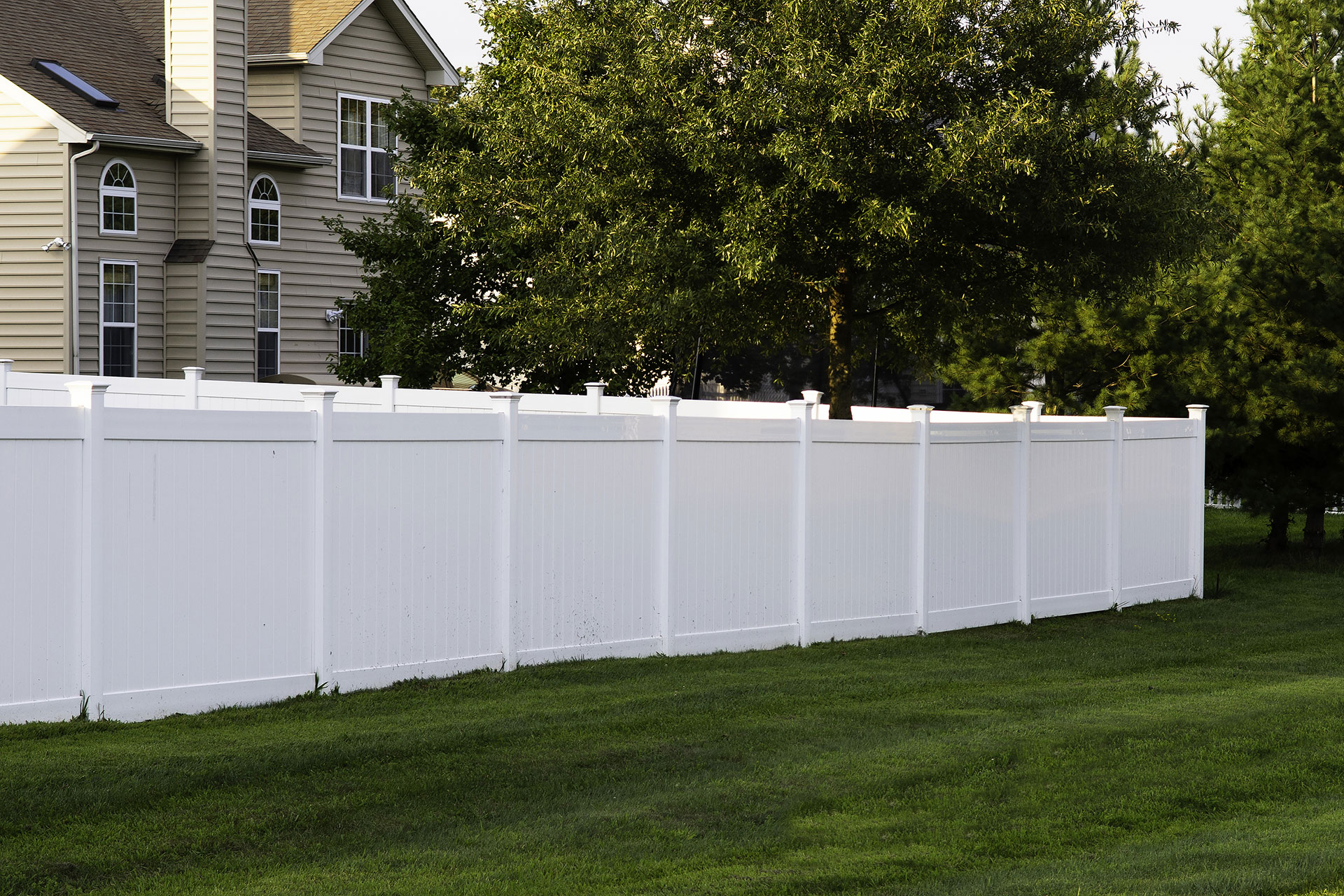 A white vinyl fence on a residential lawn.